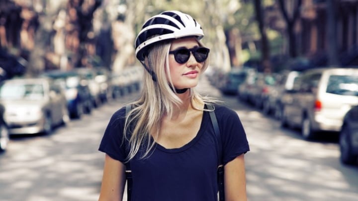 Une femme blonde avec des lunettes et un casque à vélo en ville