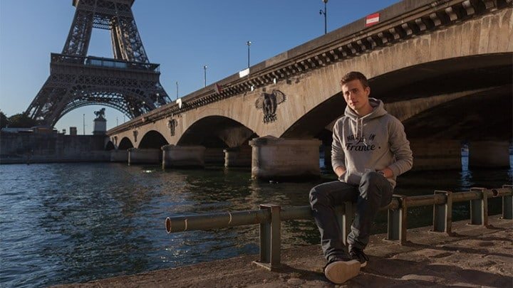 Un cycliste assis sur une borne devant un pont