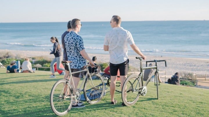 Trois hommes en vélo fixie devant une plage avec la mer