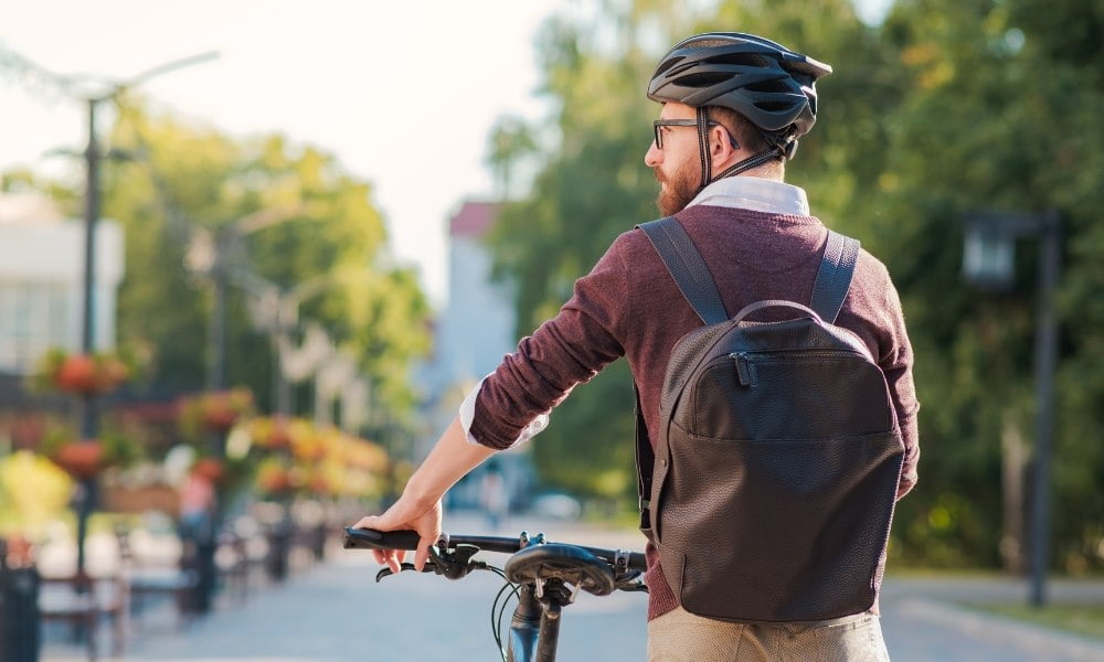 Un cycliste homme marchant et poussant son vélo dans la rue